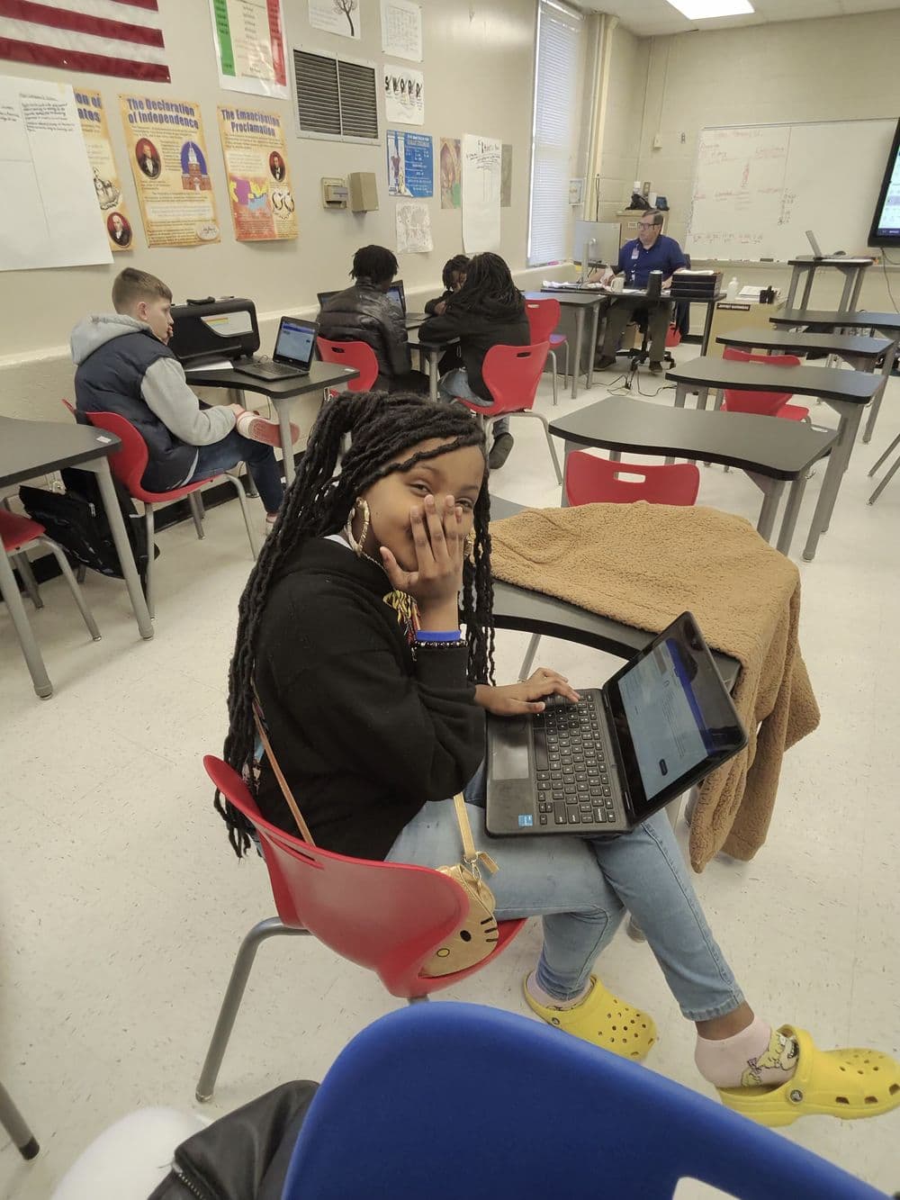 A student working through a lesson on a laptop in a classroom