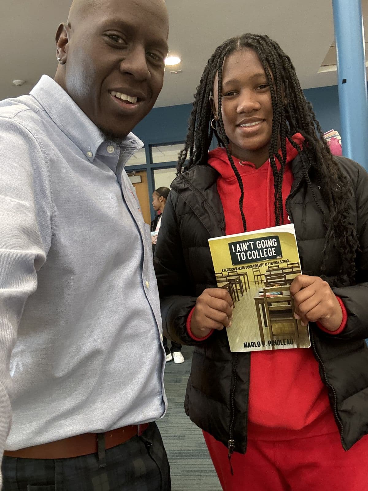 A student holding a copy of I Ain't Going to College alongside Marlo Prioleau